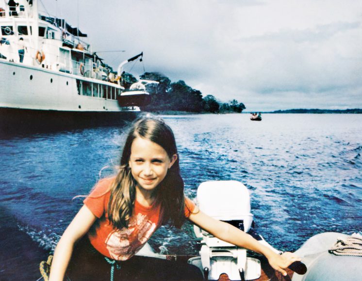 Céline Cousteau at age 9 in the Amazon, her grandfather’s famous ship Calypso in the background.