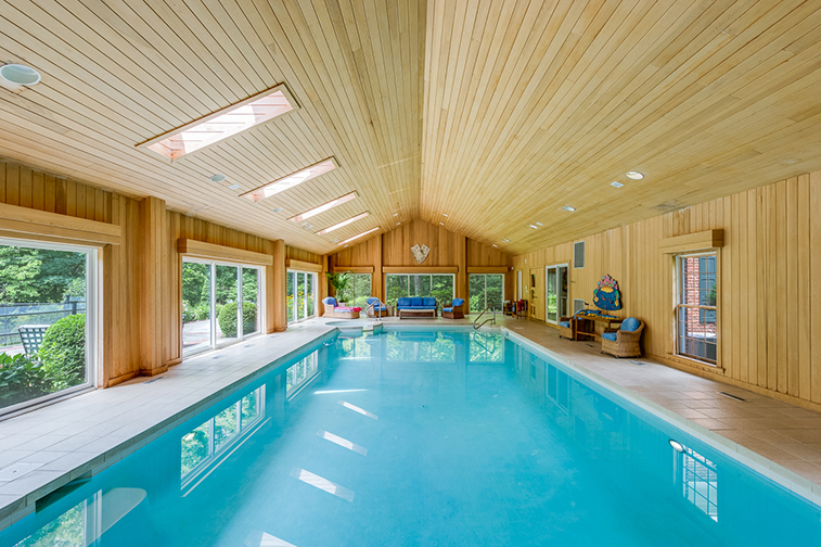 Ample sky light and sliding glass doors help flood this indoor pool with sun. Courtesy Houlihan Lawrence.