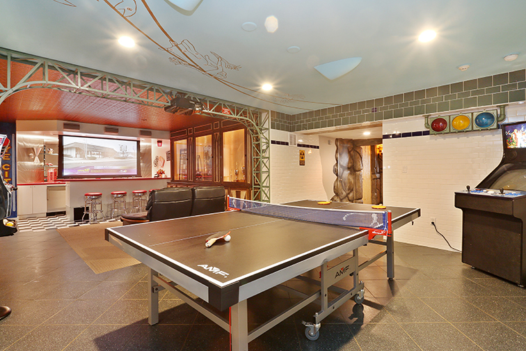 With a Ping-pong table, classic arcade machine (not pictured) and a drop projection screen for in‐home movie viewing, the basement of this Rye home is a kid’s paradise. Courtesy Houlihan Lawrence.