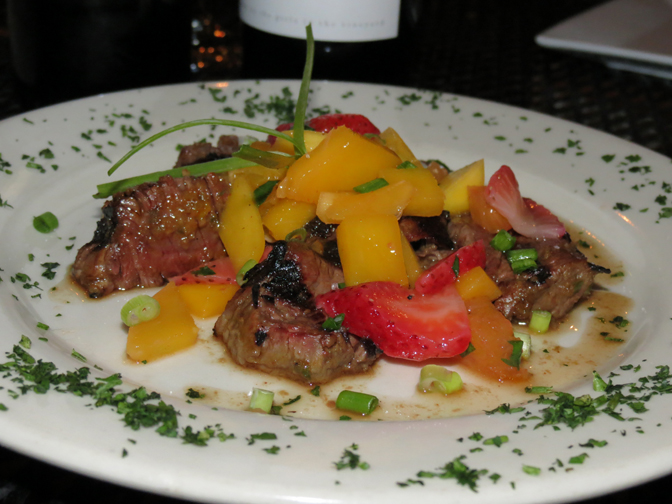 Chipotle marinated steak with a fresh fruit salad on top.