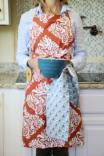 The Turtledove Ginger Orange Printed Cloth Cook’s Apron from Hen House Linens, along with the Fandango dish towel in Midnight Blue. Photograph courtesy Hen House Linens.