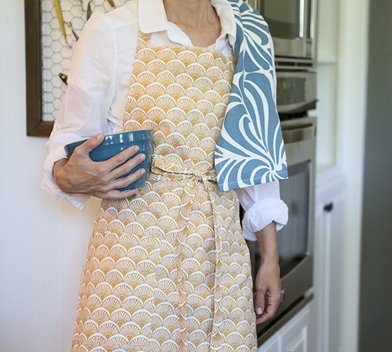 Hen House Linens offers a collection of Cook’s Aprons that includes the Fandango in Camel Yellow Printed Cloth, featured here with the Nouveau dishtowel in Midnight Blue. Photograph courtesy Hen House Linens.