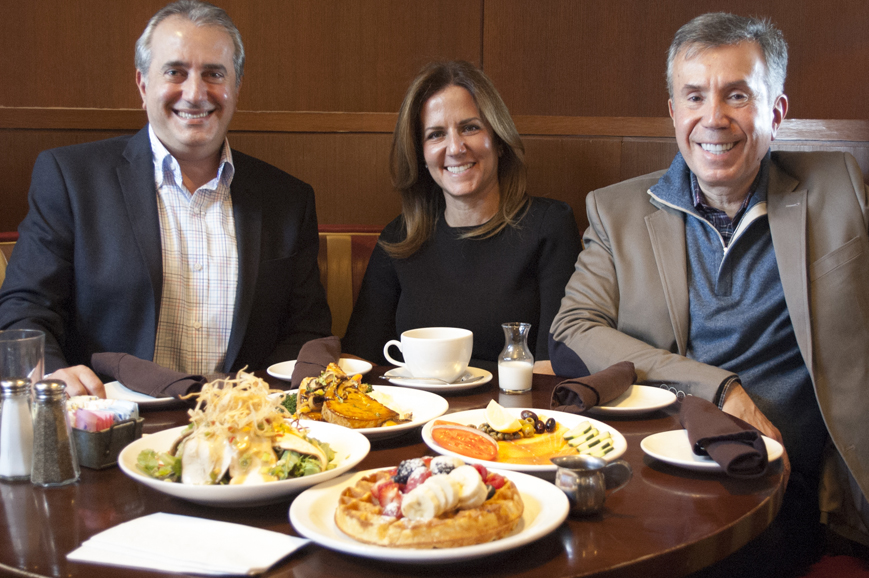 Bill, Corina and Nick Livanos with some of their best sellers at City Limits Diner in White Plains. Clockwise from top, the chicken meatloaf; the bagel with cream cheese and smoked salmon (City Limits has its own smokehouse.); the orange juice-infused waffle with fruit; and the oriental chicken salad.  Photograph by Jose Donneys.