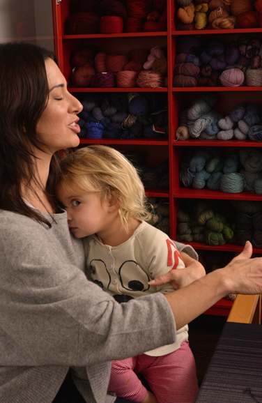 Anne-Marie Kavulla’s young daughter Adeline cozies up at the loom. Photograph by Bob Rozycki.