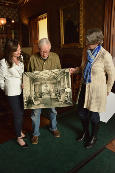 From left: Susan Gilgore, executive director; volunteer Paul Veeder; and LMMM curator Kathleen Motes Bennewitz, look over a vintage image of the Lockwood-Mathews conservatory. Photograph by Bob Rozycki.