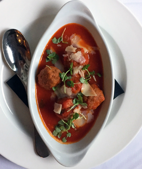 A sweet red sauce and parmesan cover an appetizer of meatballs. Photograph by Aleesia Forni.