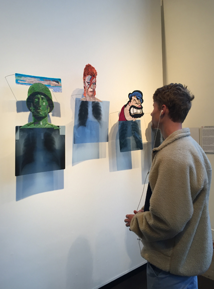 A guest at the opening reception for ArtsWestchester's Remedy exhibition observes the artwork. Photograph by Alfredo Ponce. Photograph courtesy of ArtsWestchester.