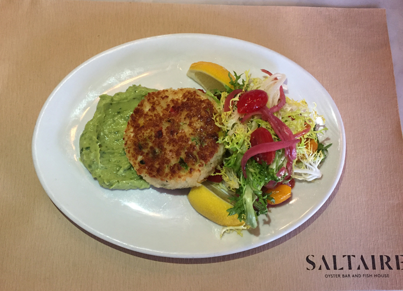 A crab cake sits atop a spread of guacamole with a fresh tomato salad. Photograph by Aleesia Forni.