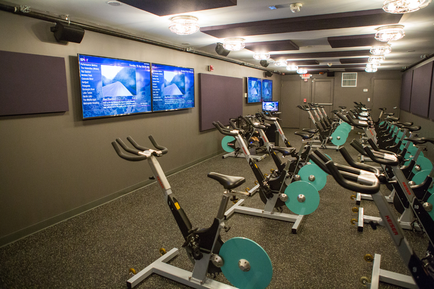 The cycling studio at TotalFusion Studios in Harrison, where cyclers can watch their performance via a personal avatar on the studio's television screens. Photograph by Starlight Studioz.