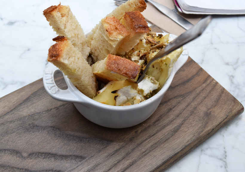 Melted Brie cheese topped with pumpkin seeds and other spices and served with toasted bread. Photograph by Aleesia Forni.