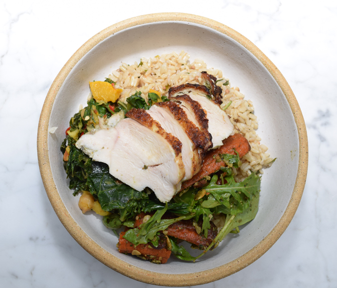 A market bowl with brown rice, herb roasted chicken breast, roasted carrots and kale, curry and delicata squash. Photograph by Aleesia Forni.