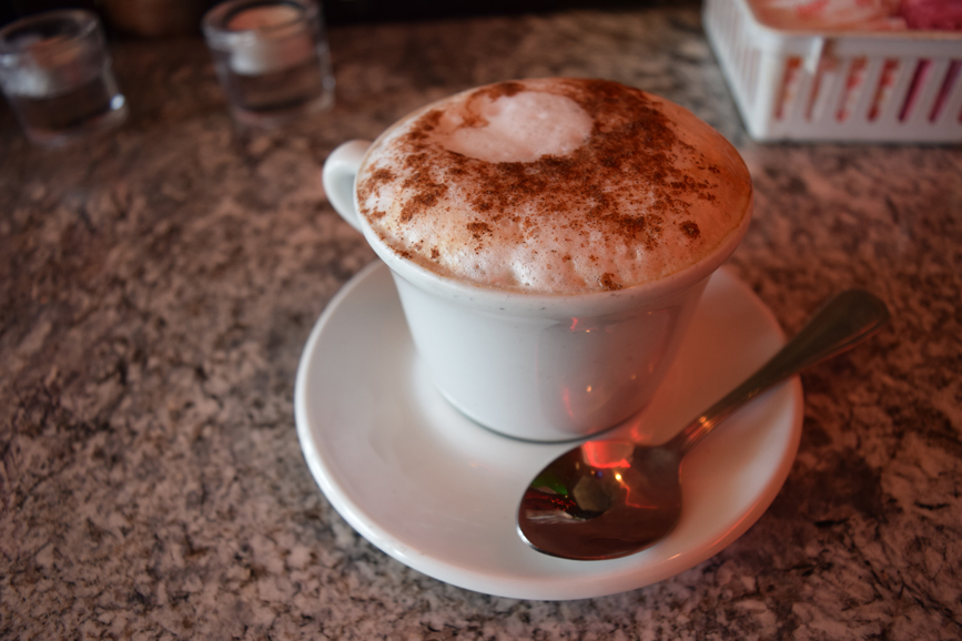 A steaming cup of cappuccino with milk foam. Photograph by Aleesia Forni.