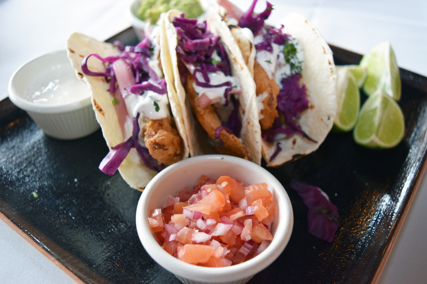 A trio of crispy fish tacos is served with creamy guacamole and salsa. Photograph by Aleesia Forni.