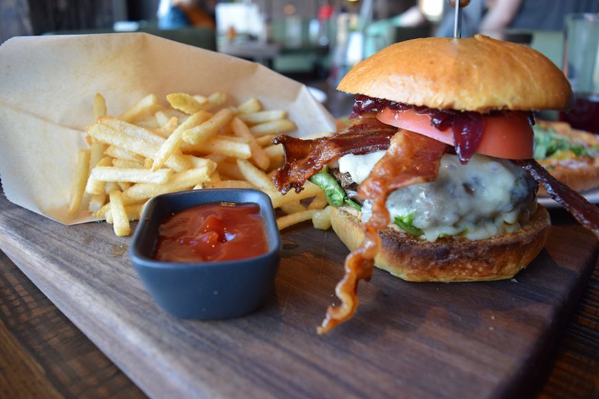 Crispy bacon overflows the juicy Perch Burger, which is served with a side of crunch french fries. Photograph by Aleesia Forni.