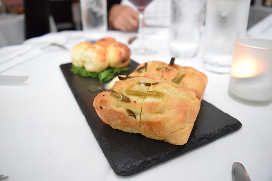 Meals are preceded by  house-made focaccia bread with buttermilk-braised garlic scapes and side of lemon butter. Photograph by Aleesia Forni.
