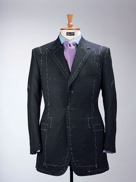 A Henry Poole & Co. bespoke suit with the correct system of white baste stitches clearly visible. When a tailor adds superfluous baste stitches to impress a customer (a trick used in the window displays of made-to-measure tailors on the west side of Savile Row), it is called “flash basting.” Henry Poole & Co. archive. Image from "Bespoke: The Masters Tailors of Savile Row" (Thames & Hudson.)