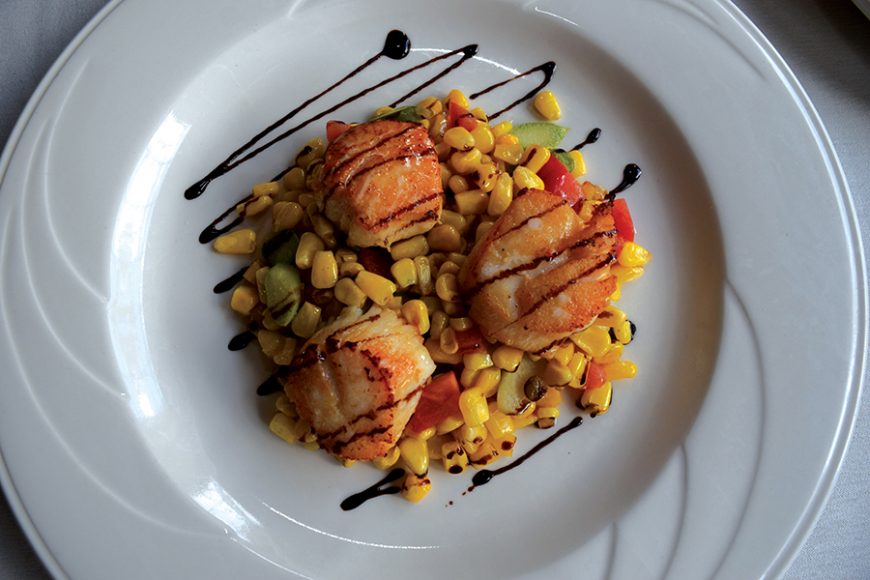Scallops served over a bed of veggies and a balsamic drizzle. Photograph by Aleesia Forni.