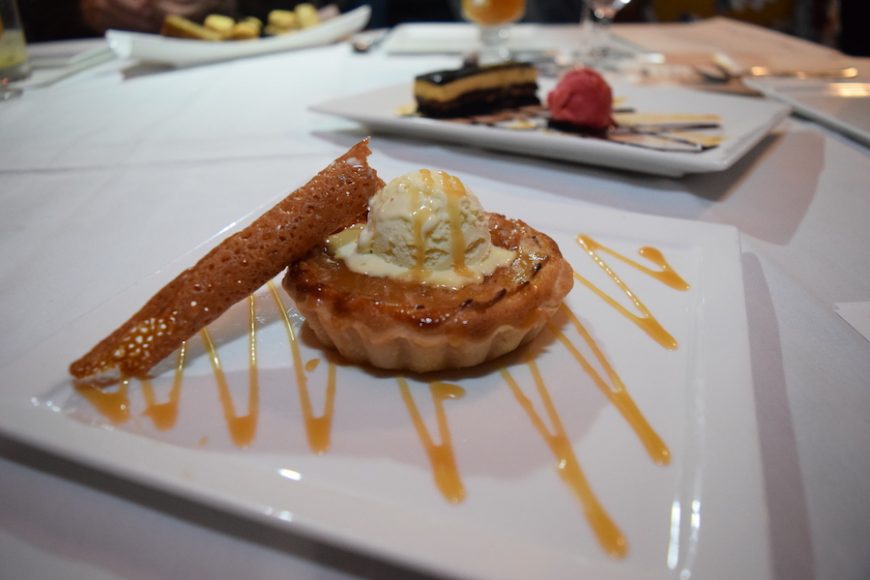An apple tart dessert is topped with vanilla ice cream. Photograph by Aleesia Forni.