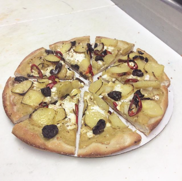 Hummus pizza, topped with goat cheese, Kalamata olives, sliced Yukon potatoes, cherry peppers and olive oil. Photograph courtesy Famous Greek Kitchen.