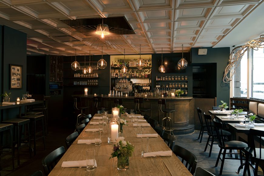 The dining area features a wooden bar, industrial fixtures and faux white branches that line the windows. Photograph by Morgan Ione Yeager.