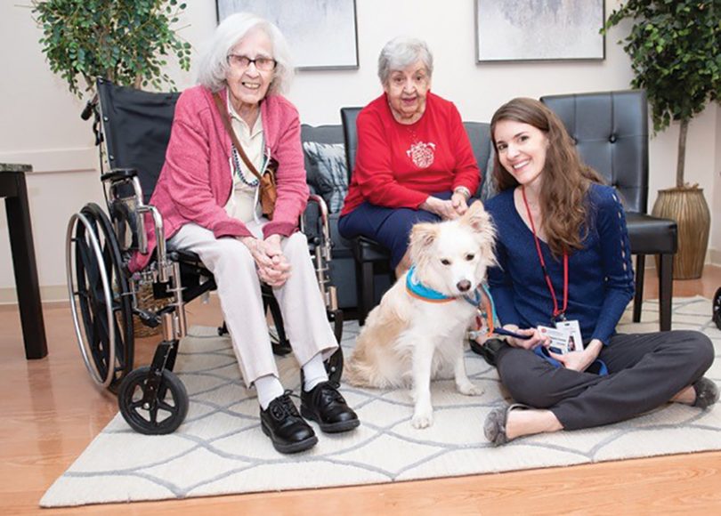 United Hebrew residents Carol Virrill (left) and Angela Fasano enjoy a visit with Tinsley and her owner, Stephanie Bostaph. Photograph courtesy MiMA Photography.