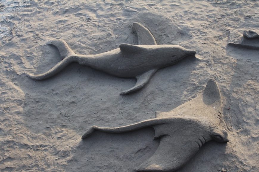 Sand sculptures await their fate as the tide rises.