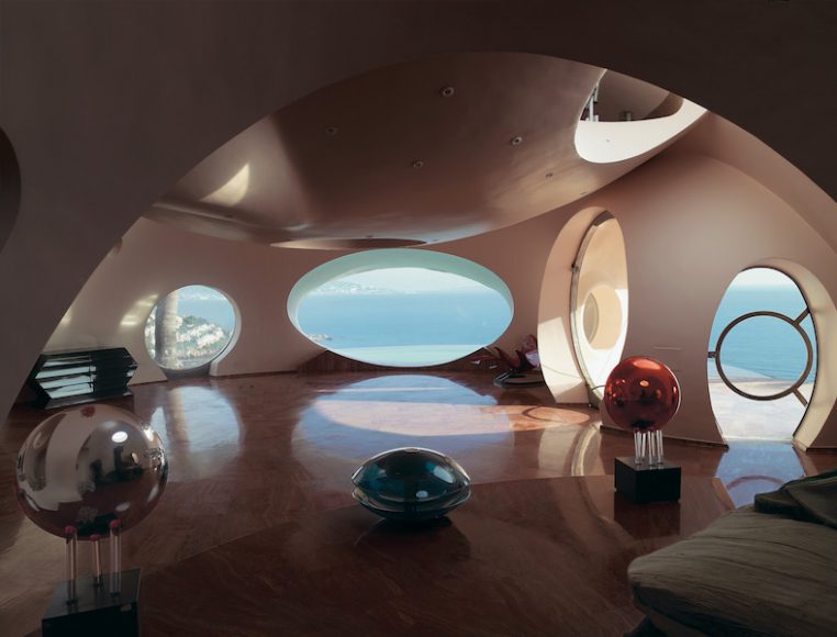 Antti Lovag, Palais Bulles, 1989. Théoule-sur-Mer, Cannes, France. The infinity-style swimming pool lends a further layer of surreal abstraction to the house. Inside, the collaboration between Antti Lovag and Pierre Cardin resulted in equally unexpected interiors. Photograph by Richard Powers, as featured in “The Iconic House: Architectural Masterworks Since 1900.” Courtesy Thames & Hudson.