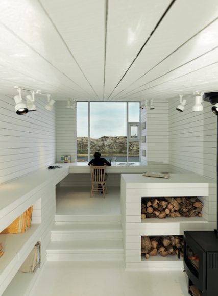 Saunders Architecture: Bridge Studio, Deep Bay, Fogo Island, Newfoundland, Canada. The building is orientated towards the view across an inland pool, and accessed over a bridge to the rear. Photograph © 2019 Bent René Synnevåg. Courtesy Thames & Hudson.