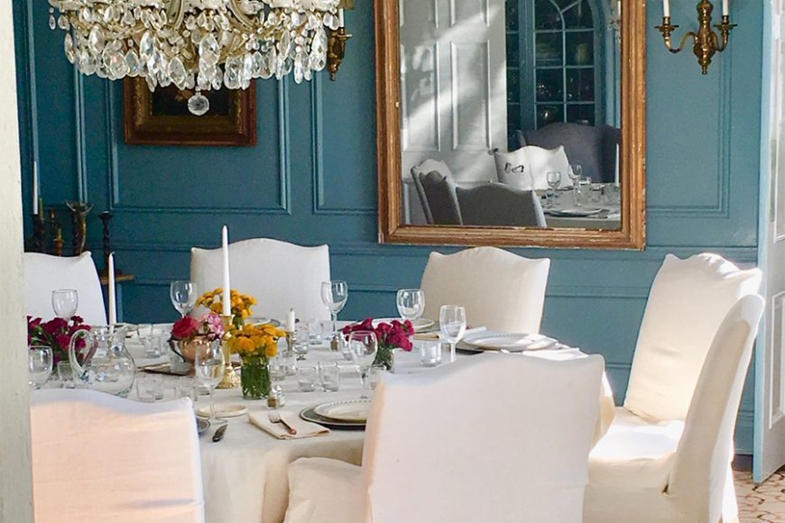 Benjamin Moore Jamestown Blue painted walls give a sense of history to this large dining room, which includes an 86-inch round Ralph Lauren slip-covered table.