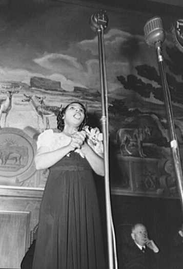 Marian Anderson singing at the 1943 dedication of a mural installed in the United States Department of the Interior, commemorating the outdoor concert she gave at the Lincoln Memorial in 1939  after the Daughters of the American Revolution refused to allow her to sing in Constitution Hall. Photograph by Gordon Parks.