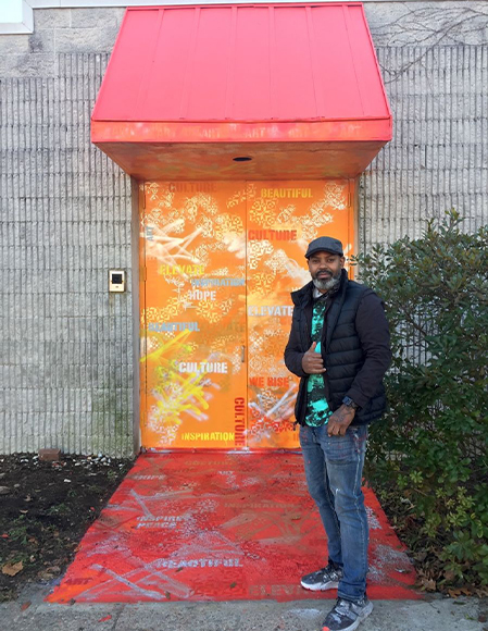 Lance Johnson with his mural "Abundance of Culture." Photograph by Barry L. Mason.